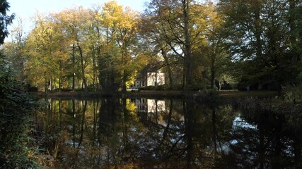 Wall Mural - Big landhouse in Autumn forest with water reflections in lake