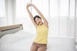 © Nitiphol - Young woman wake up in the morning and stretching on her bed
