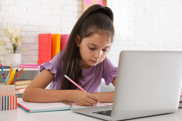 Canvas Print - Pretty preteen girl doing homework with laptop at table