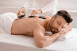 © Prostock-studio - Joyful man having hot stone massage at luxury spa