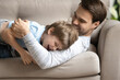 © fizkes - Close up overjoyed young father and adorable son hugging, lying on cozy couch at home, excited loving dad and little boy child cuddling, relaxing on sofa, family enjoying leisure time together