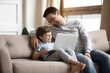 © fizkes - Happy father and little boy using laptop at home together, browsing apps, playing game, enjoying leisure time with device, smiling loving dad hugging adorable son, teaching to use computer