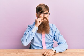 Wall Mural - young irish redhead man wearing business shirt and tie sitting on the table mouth and lips shut as z