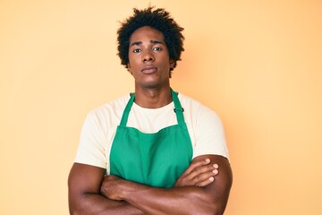 Sticker - Handsome african american man with afro hair wearing waiter apron skeptic and nervous, disapproving expression on face with crossed arms. negative person.