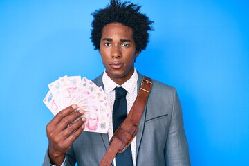 Canvas Print - Handsome african american man with afro hair holding mexican pesos thinking attitude and sober expression looking self confident