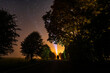 © nikwaller - Overhead milky way with stars in clear summer night. Country side. Young couple standing with bright torch light.