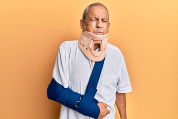 Poster - Handsome mature senior man wearing cervical collar and arm on sling puffing cheeks with funny face. mouth inflated with air, crazy expression.