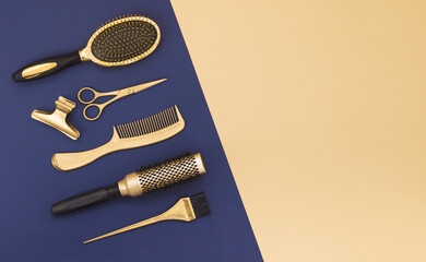 Hairdressing tools on a blue background and a yellow sheet with space for text. Gold hair salon accessories, comb, scissors, hair clip. Modern design.