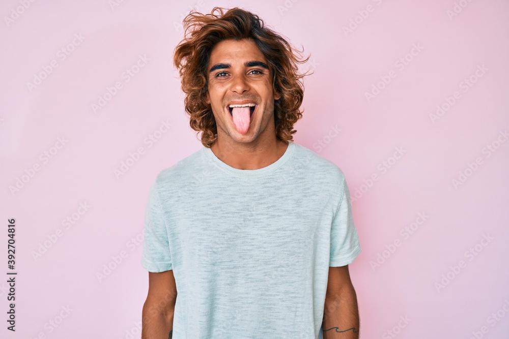 Young hispanic man wearing casual clothes sticking tongue out happy with funny expression. emotion concept.