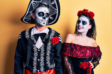 Poster - Young couple wearing mexican day of the dead costume over yellow looking away to side with smile on face, natural expression. laughing confident.