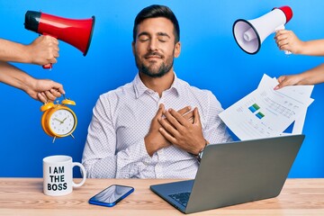 Sticker - Handsome hispanic man working at the office being stressed out smiling with hands on chest with closed eyes and grateful gesture on face. health concept.