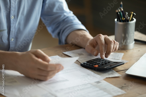 Obraz na płótnie Personal finance management, accounting concept. Close up view man sitting at table using calculator performs arithmetic operations calculates costs per month, manage family budget, control expenses