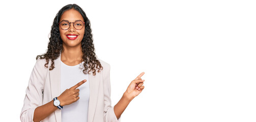 Young african american girl wearing business clothes smiling and looking at the camera pointing with two hands and fingers to the side.