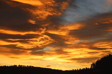 Dramatic Sky In Dawn Over Mountains. Before Sunrise, The Sun Sets Over Scandinavia's Forest And Woods Skyline. The Violent Golden Cloud Is Like A Burning Flame.