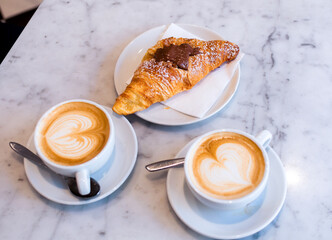 Croissant y dos cafés en una mesa 