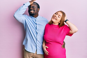 Sticker - Young interracial couple expecting a baby, touching pregnant belly smiling confident touching hair with hand up gesture, posing attractive and fashionable