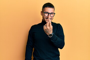 Poster - Handsome man with tattoos wearing turtleneck sweater and glasses beckoning come here gesture with hand inviting welcoming happy and smiling