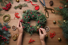 Florist Making Beautiful Christmas Wreath At Wooden Table, Top View