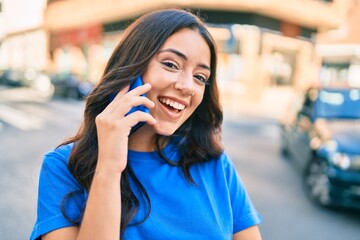 Sticker - Young hispanic woman smiling happy talking on the smartphone at the city.