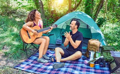 Poster - Middle age couple  of hiker smiling happy camping at the forest. Sitting on the floor singing song playing classical guitar