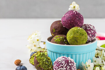 Wall Mural - Energy balls and bites in chocolate glaze with flowers on white background . Healthy vegan snacks. Raw sweet dessert