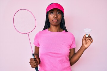 Sticker - African american woman with braids holding badminton racket relaxed with serious expression on face. simple and natural looking at the camera.