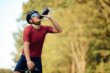 Wall Mural - Exhausted road cyclist drinking water from bottle