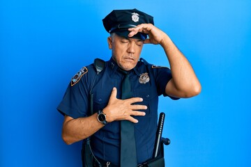 Canvas Print - Handsome middle age mature man wearing police uniform touching forehead for illness and fever, flu and cold, virus sick