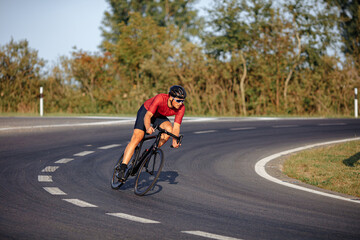 Wall Mural - Strong athlete riding bike with high speed on road