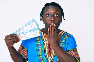 Canvas Print - Young african american man with braids wearing ethnic clothes holding airplane boarding pass covering mouth with hand, shocked and afraid for mistake. surprised expression