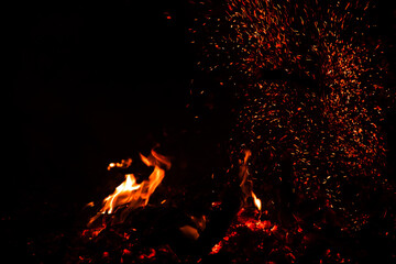 Burning red hot sparks rise from large fire in the night. Fire flames sparks background. Abstract dark glitter fire particles lights.