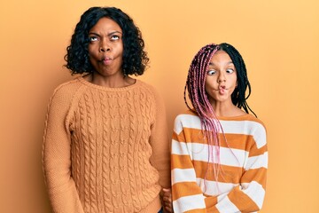 Sticker - Beautiful african american mother and daughter wearing wool winter sweater making fish face with lips, crazy and comical gesture. funny expression.