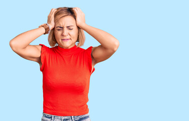 Wall Mural - Young blonde woman wearing casual clothes suffering from headache desperate and stressed because pain and migraine. hands on head.