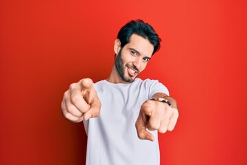 Young hispanic man wearing casual white tshirt pointing to you and the camera with fingers, smiling positive and cheerful