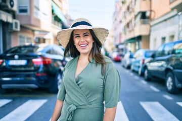 Wall Mural - Young hispanic woman on vacation smiling happy walking at street of city