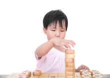 Chinese Three-year-old Girl Stacking Chinese Chess Pieces On The Table In Front Of White Background