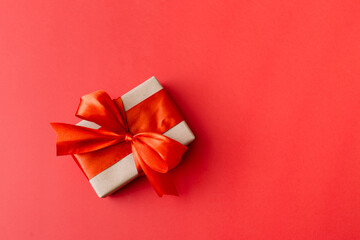 present box with red bow on red background. flat lay, top view, copy space.