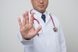 © Chanakon - Close Up Physician in white coat, stethoscope showing rejecting gesture by.stop palm sign in front of camera isolated on white background.