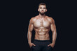 © satyrenko - Muscular and fit young bodybuilder fitness male model posing isolated on black background