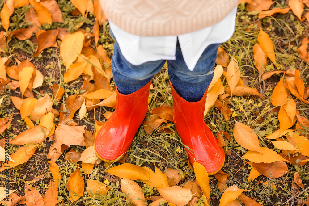 Cute little boy wearing gumboots in autumn park