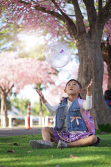 Asian little girl in garden under the blossom sakura tree background