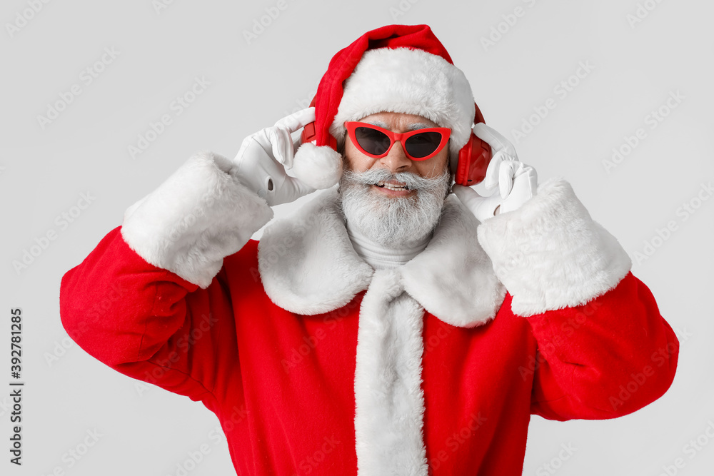 Cool Santa Claus listening to music on grey background