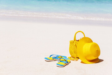 Wall Mural - Yellow round hat, beach bag,  and flip flops on a tropical beach, summer beach vacation concept