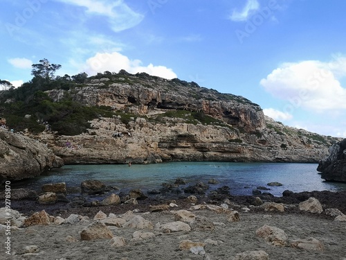 Obraz Dibond sandy beach and rocks with turquoise blue water and cliff in the background