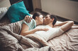 © Strelciuc - Upper view photo of a young couple lying in bed and kissing while embracing under a quilt