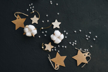 Decorative stars and white cotton on a black background, top view. Flat lay composition