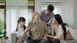 © ChayTee - Asian elderly senior male grandpa sitting at sofa couch at home living room on quarantine in concept healthcare, chronic health issue or low back pain in retired older people with family.