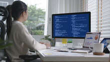 Back Rear View Of Young Asian Woman, Freelance Data Scientist Work Remotely At Home Coding Programing On Big Data Mining, AI Data Engineering, IT Technician Works On Artificial Intelligence Project.