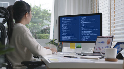 back rear view of young asian woman, freelance data scientist work remotely at home coding programin