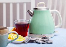 Turquoise Electric Kettle, Cup, Tea Bags And Sliced Lemon On Wooden Background